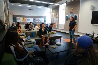 Speaker standing before students sitting on couches with laptops